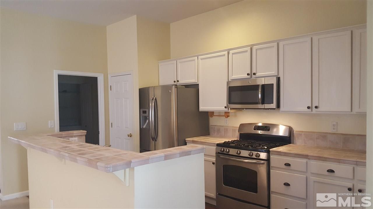 10281 Wolf Ridge Way Reno, NV 89521 - Photo 3 of 22 a kitchen with stainless steel appliances white cabinets and a stove top oven