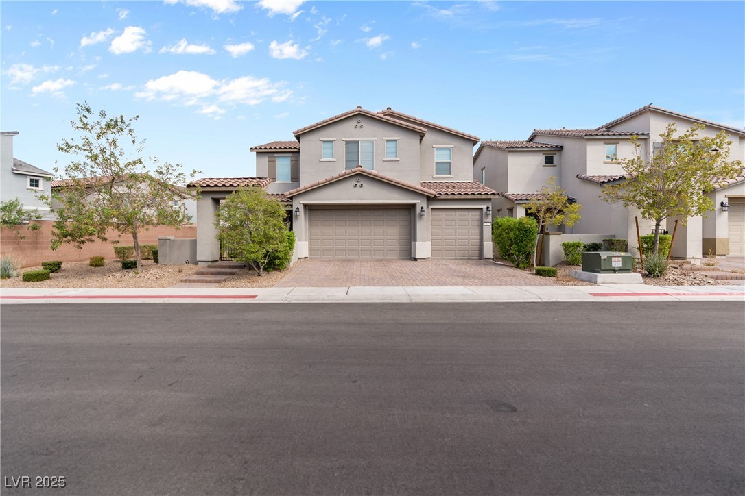 Mediterranean / spanish house with stucco siding, decorative driveway, a garage, and a tiled roof