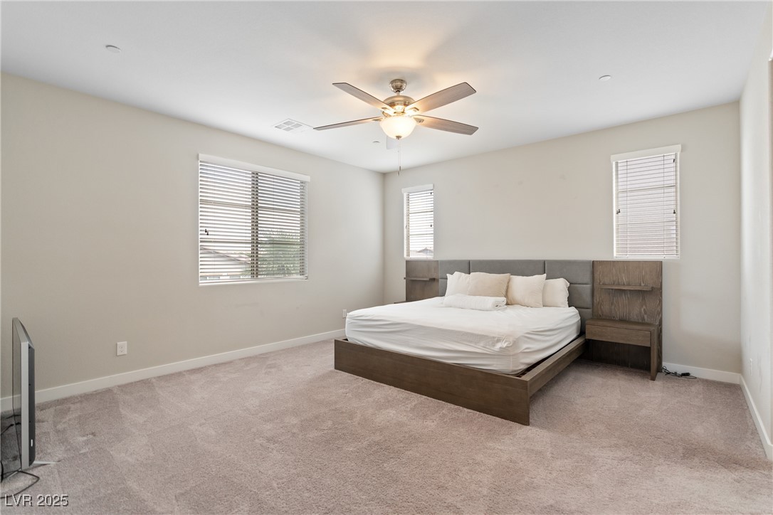 12 Papavero Court Henderson, NV 89011 - Photo 6 of 17 Bedroom featuring light carpet, multiple windows, and a ceiling fan
