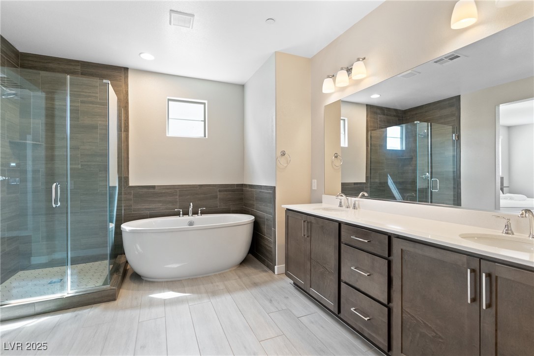 12 Papavero Court Henderson, NV 89011 - Photo 7 of 17 Full bath with plenty of natural light, a freestanding bath, a shower stall, tile walls, and double vanity