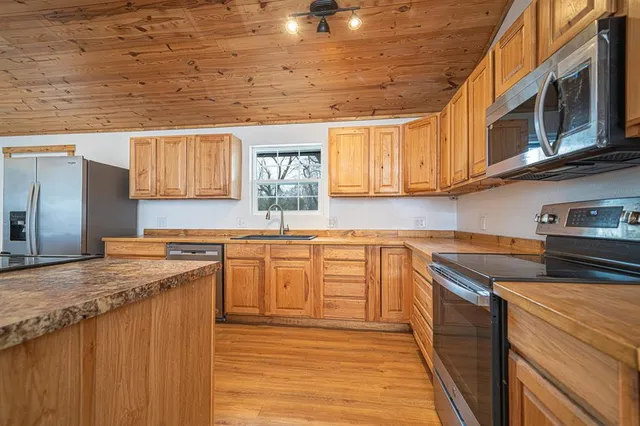 a kitchen with stainless steel appliances granite countertop wooden cabinets a stove top oven a sink and dishwasher