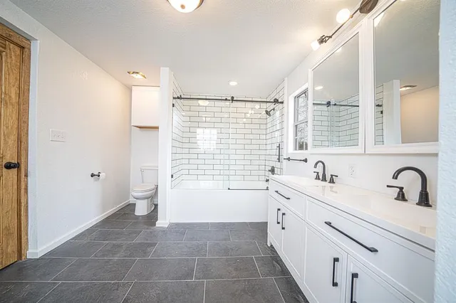a bathroom with a double vanity sink a toilet and a bathtub