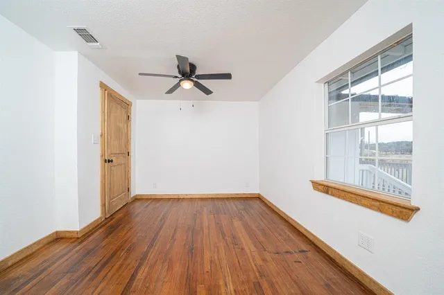 a view of empty room with wooden floor and fan