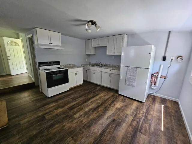 a kitchen with granite countertop a stove a sink and a refrigerator