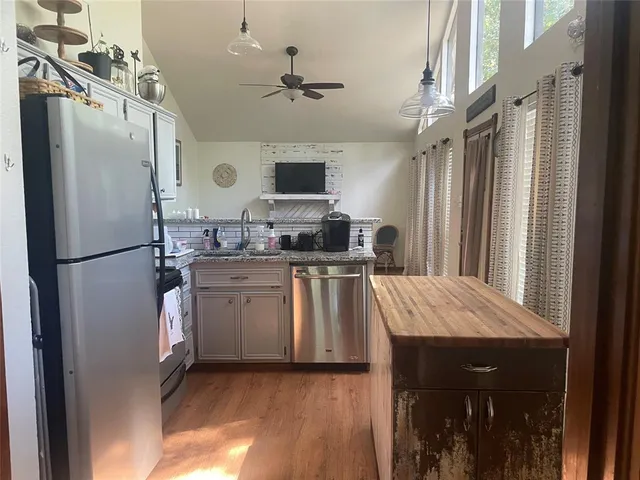 a kitchen with kitchen island a counter top space a sink stainless steel appliances and cabinets
