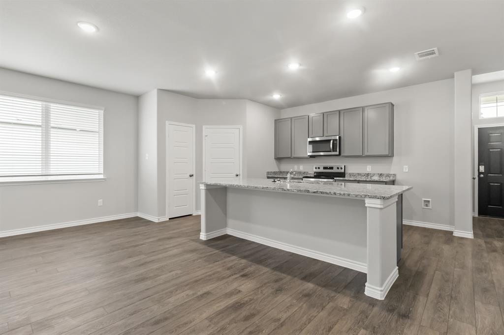 10656 Stag Lane Crowley, TX 76036 - Photo 2 of 13 a kitchen with granite countertop white cabinets and wooden floor