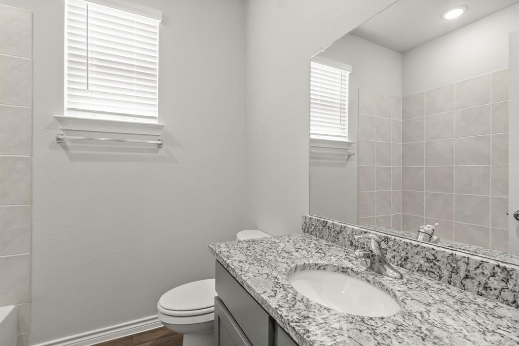10656 Stag Lane Crowley, TX 76036 - Photo 9 of 13 a bathroom with a granite countertop toilet a sink and mirror