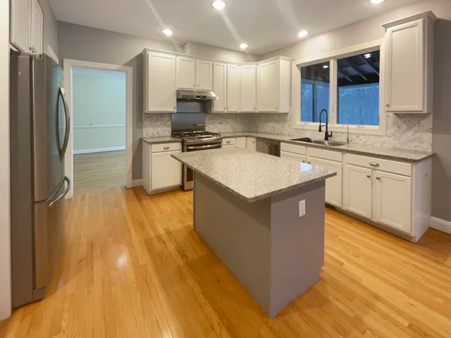 a large kitchen with stainless steel appliances granite countertop a sink a stove a refrigerator and a microwave