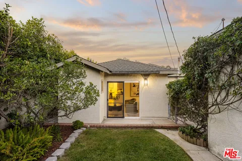 a view of a house with a small yard plants and a large tree