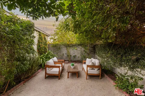 a patio with table and chairs and potted plants