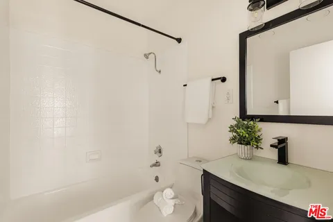 a bathroom with a granite countertop sink a toilet and shower