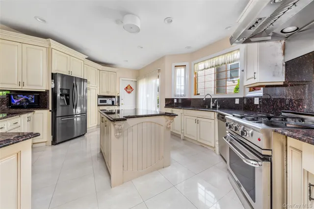a kitchen with granite countertop a sink stainless steel appliances white cabinets and a window
