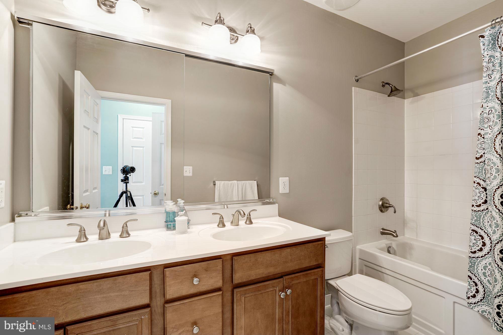 25013 Riding Center Drive Chantilly, VA 20152 - Photo 20 of 28 a bathroom with a sink a toilet a mirror a vanity and shower