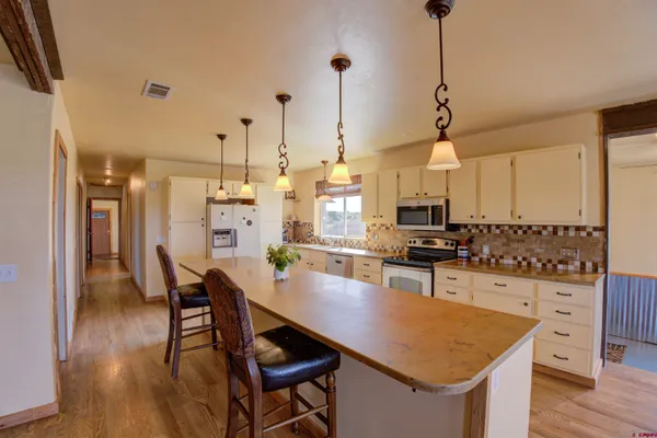 a kitchen with stainless steel appliances kitchen island granite countertop a table chairs in it and white cabinets