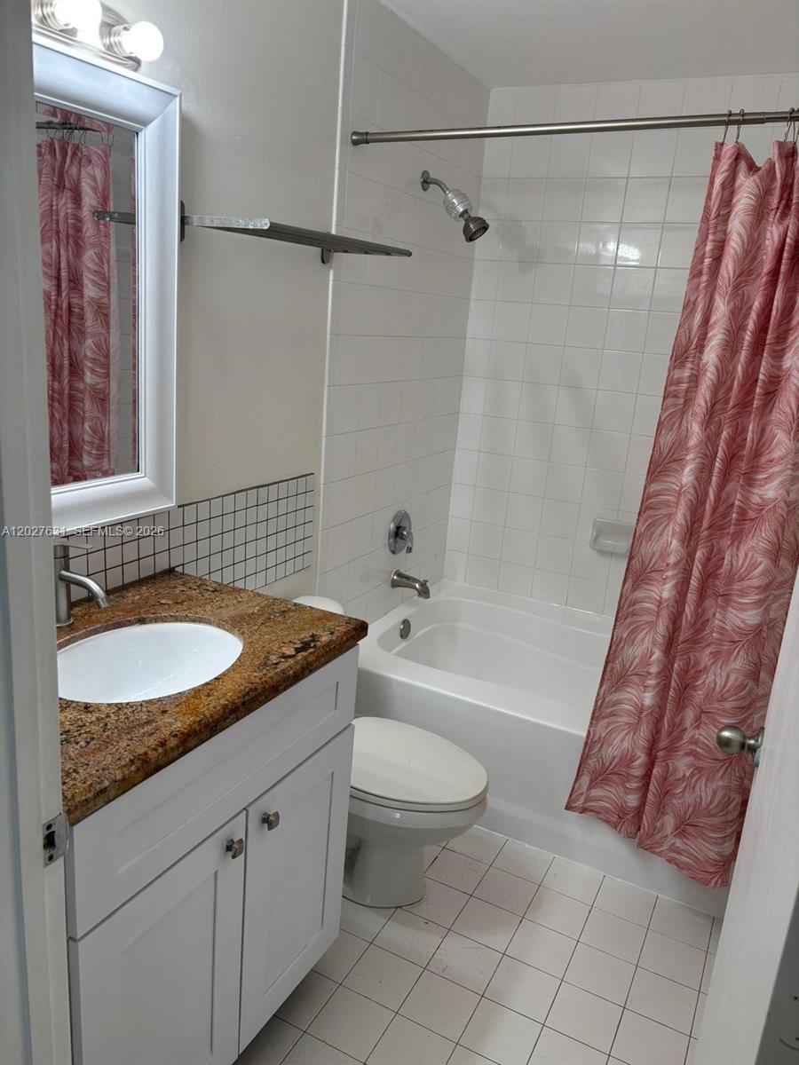 2081 Renaissance Boulevard, Unit 306 Miramar, FL 33025 - Photo 11 of 22 a bathroom with a granite countertop sink a toilet a mirror a bathtub and shower