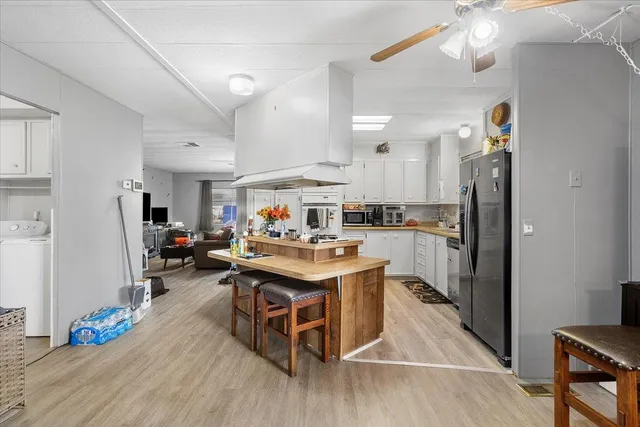 a living room with stainless steel appliances furniture a rug and a kitchen view