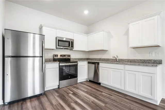 a kitchen with granite countertop a refrigerator stove top oven and sink