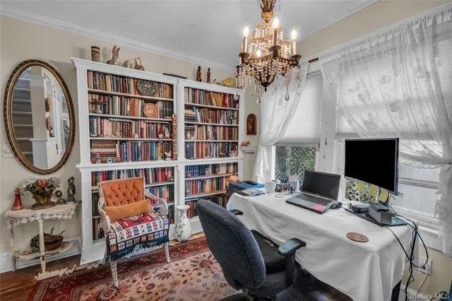 a reading room with furniture a chandelier and a bookshelf