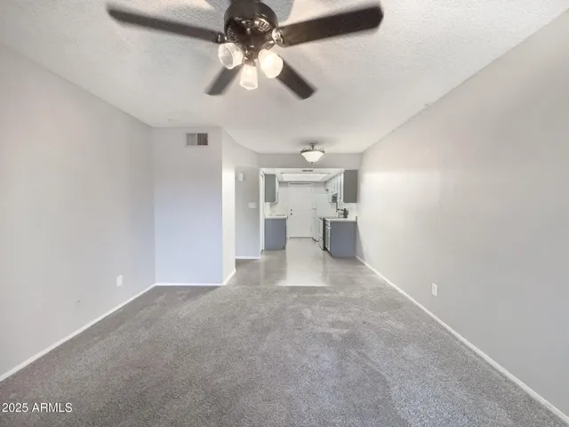 an empty room with a chandelier fan and windows