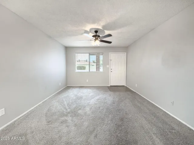 an empty room with a chandelier fan and windows
