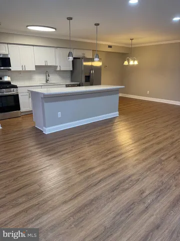 a view of a kitchen with kitchen island white cabinets and wooden floor