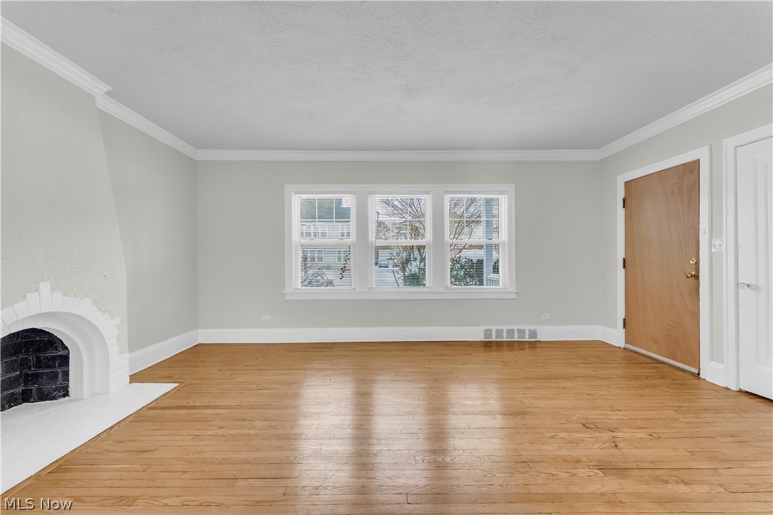 3318 Milverton Road, Unit 1/DN Shaker Heights, OH 44120 - Photo 2 of 21 Bright room featuring hardwood floors, a white fireplace, and three windows providing natural light