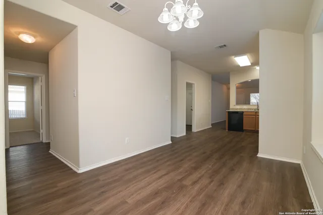 a view of a hallway with wooden floor and a kitchen