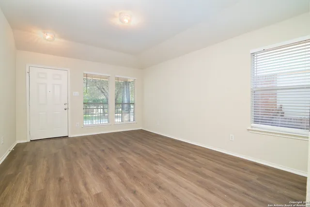 a view of an empty room with wooden floor and a window