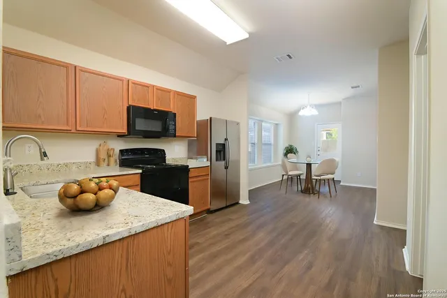a kitchen with stainless steel appliances kitchen island granite countertop a table chairs in it and wooden floors