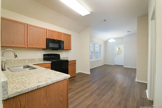 a kitchen with granite countertop a stove and a wooden floors