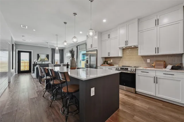 a kitchen with stainless steel appliances granite countertop a stove a sink dishwasher a microwave oven and a dining table with wooden floor