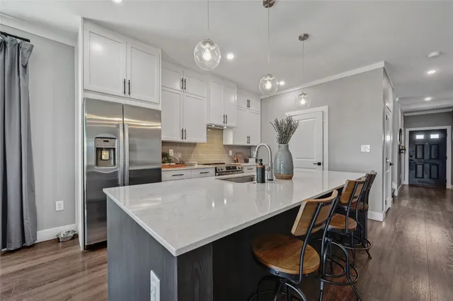a kitchen with stainless steel appliances a table chairs refrigerator and wooden cabinets