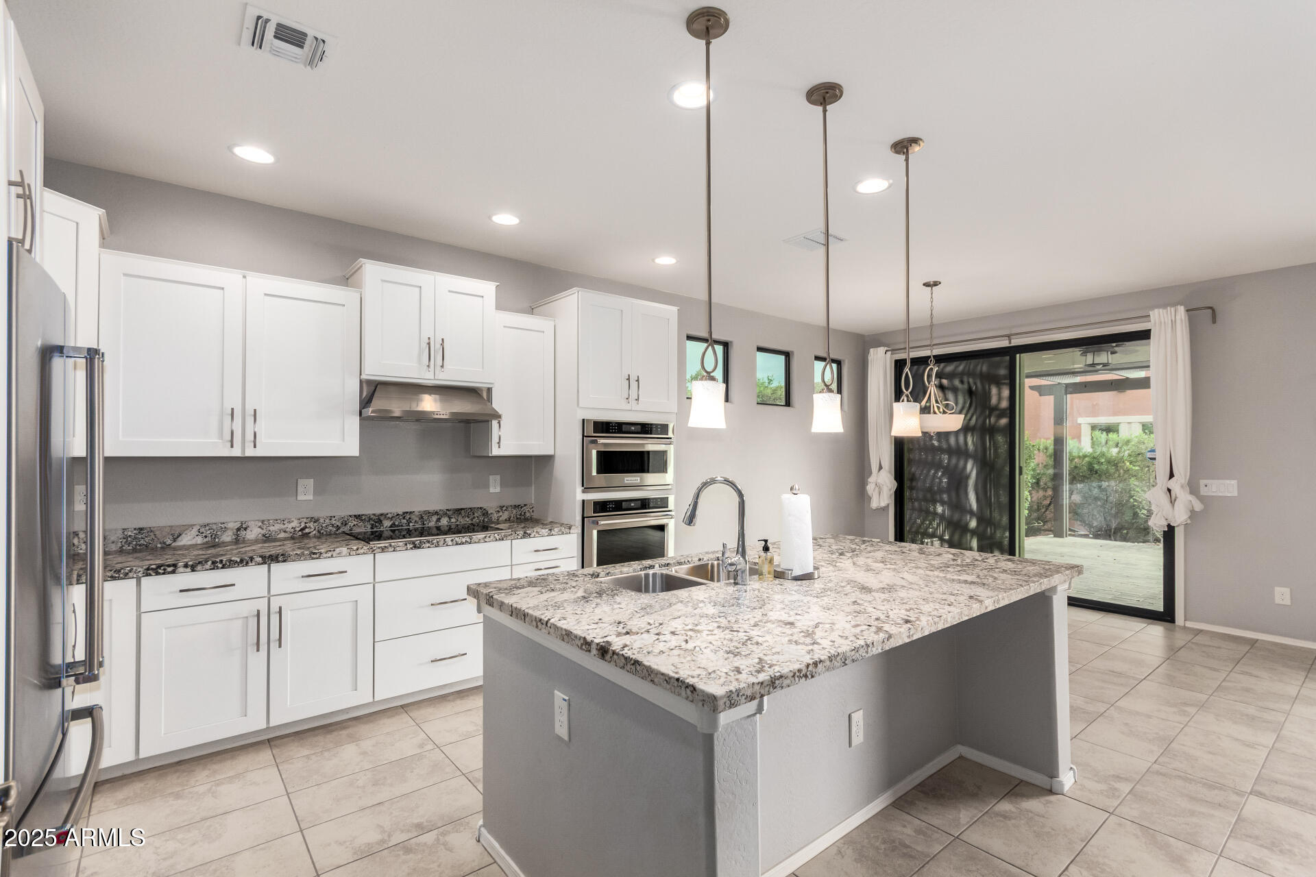 41609 West Summer Wind Way Maricopa, AZ 85138 - Photo 15 of 40 a kitchen with kitchen island granite countertop a stove a sink a oven a counter space and cabinets