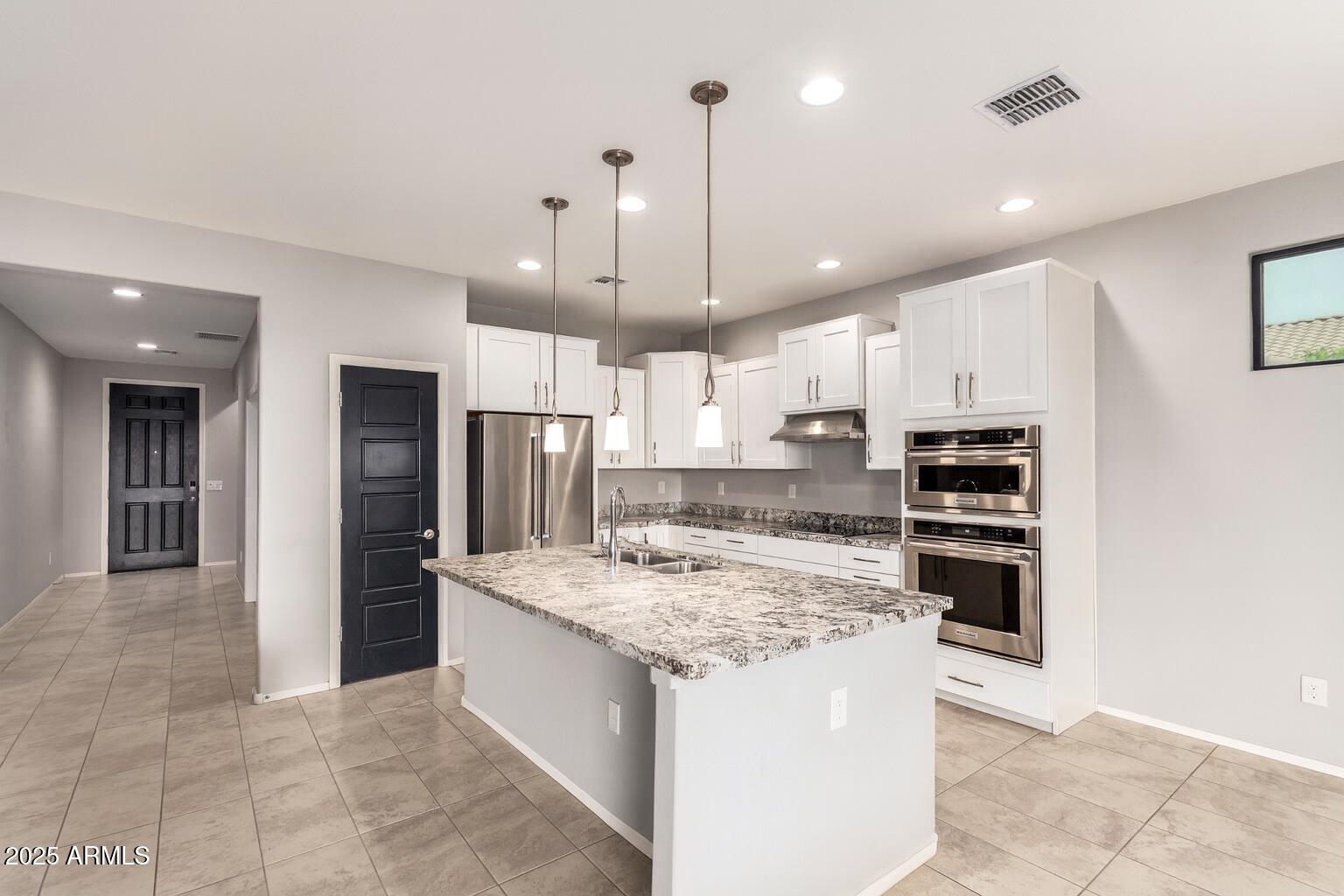 41609 West Summer Wind Way Maricopa, AZ 85138 - Photo 16 of 40 a kitchen with stainless steel appliances kitchen island granite countertop a refrigerator and a stove top oven