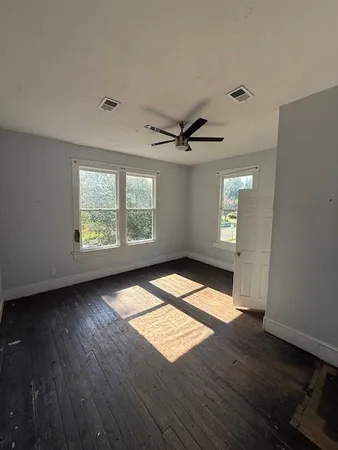 a view of empty room with wooden floor and fan
