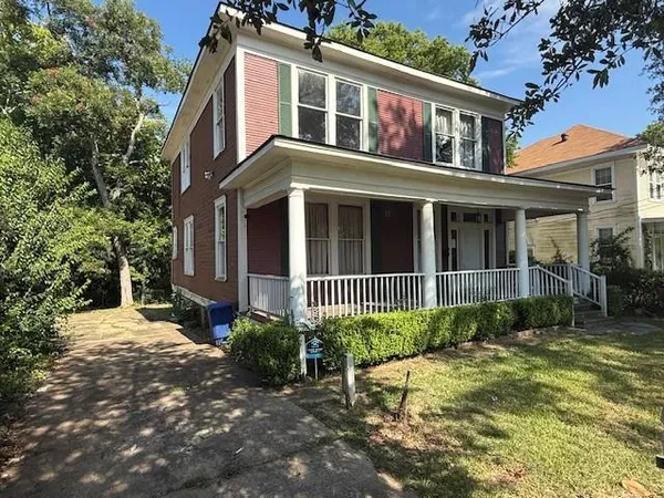 a view of a brick house with many windows plants and large tree