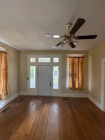 a view of an empty room with a window and wooden floor