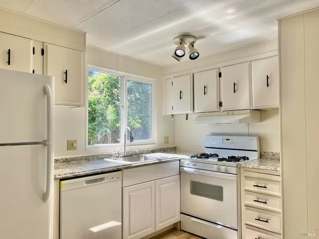 a kitchen with granite countertop white cabinets and white appliances