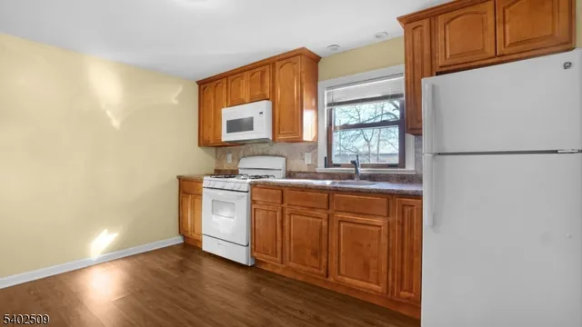 a kitchen with stainless steel appliances granite countertop a refrigerator a sink dishwasher a stove with wooden cabinets and floor