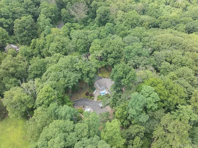 an aerial view of residential house with outdoor space and trees all around