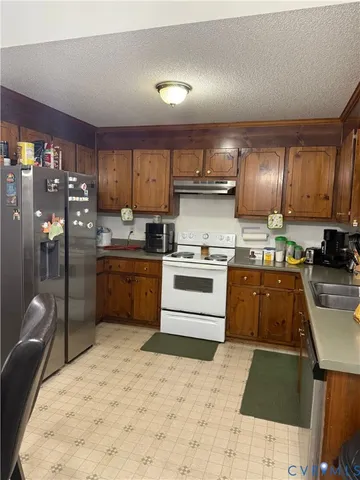 a kitchen with stainless steel appliances kitchen island granite countertop a sink stove and refrigerator