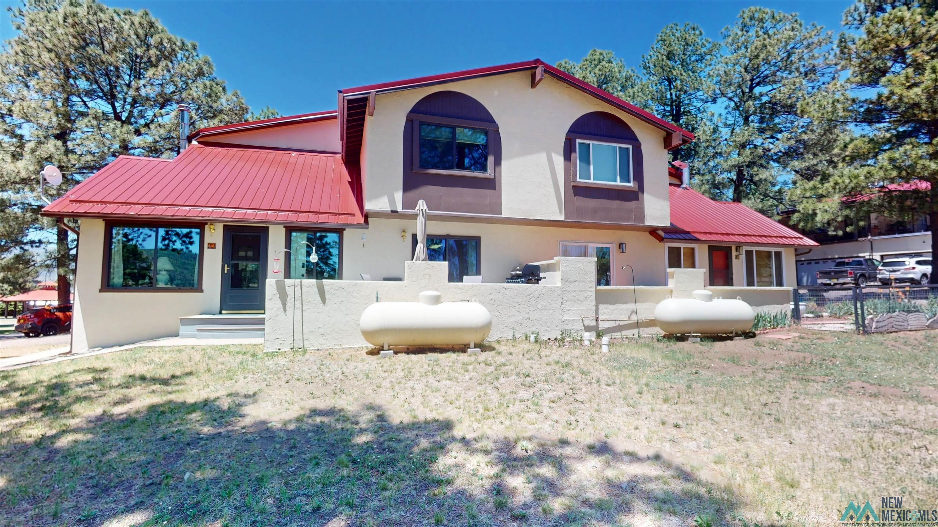 23 Pendaries Lane Rociada, NM 87742 - Photo 21 of 26 Multi-level stucco exterior featuring a red metal roof and multiple windows