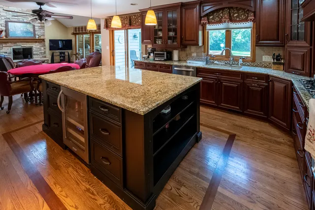 a kitchen with stainless steel appliances granite countertop wooden cabinets and wooden floors
