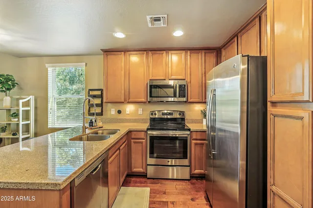 a kitchen with stainless steel appliances granite countertop refrigerator a sink a stove a washer dryer and a dining table with wooden cabinet