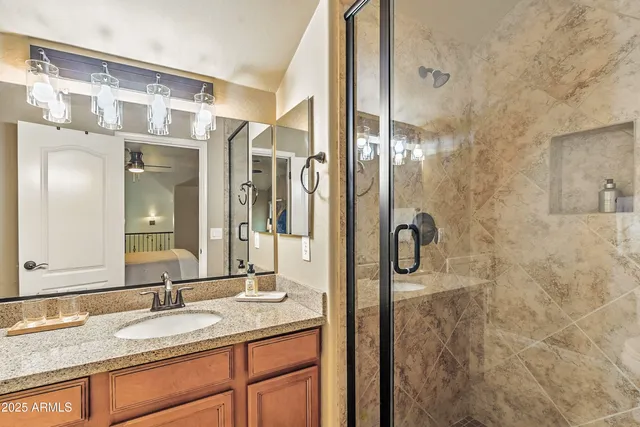 a bathroom with a granite countertop shower a sink and a mirror