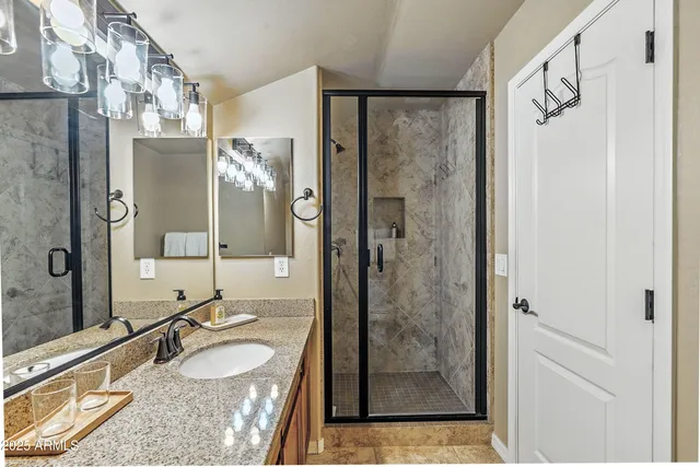 a bathroom with a granite countertop shower sink and mirror