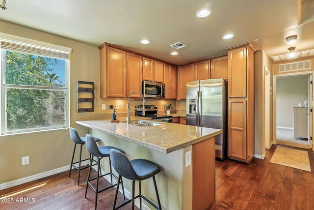 a kitchen with stainless steel appliances granite countertop a refrigerator a sink a stove a dining table and chairs