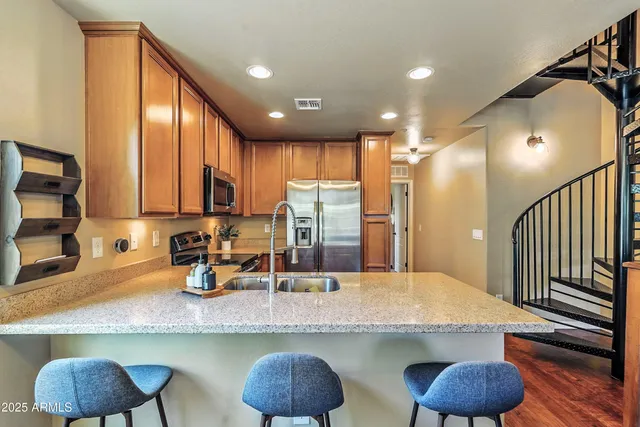 a kitchen with kitchen island granite countertop wooden cabinets and a refrigerator