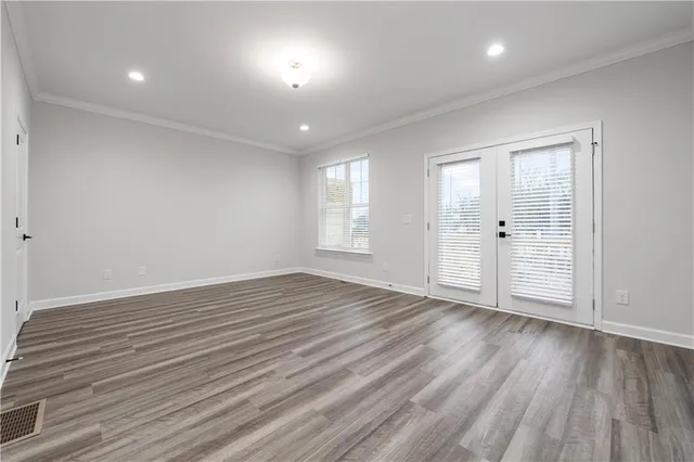 an empty room with wooden floor and windows