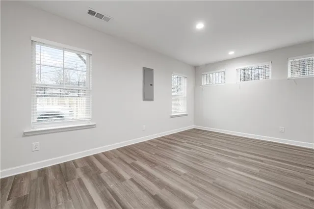 an empty room with staircase ceiling fan and windows
